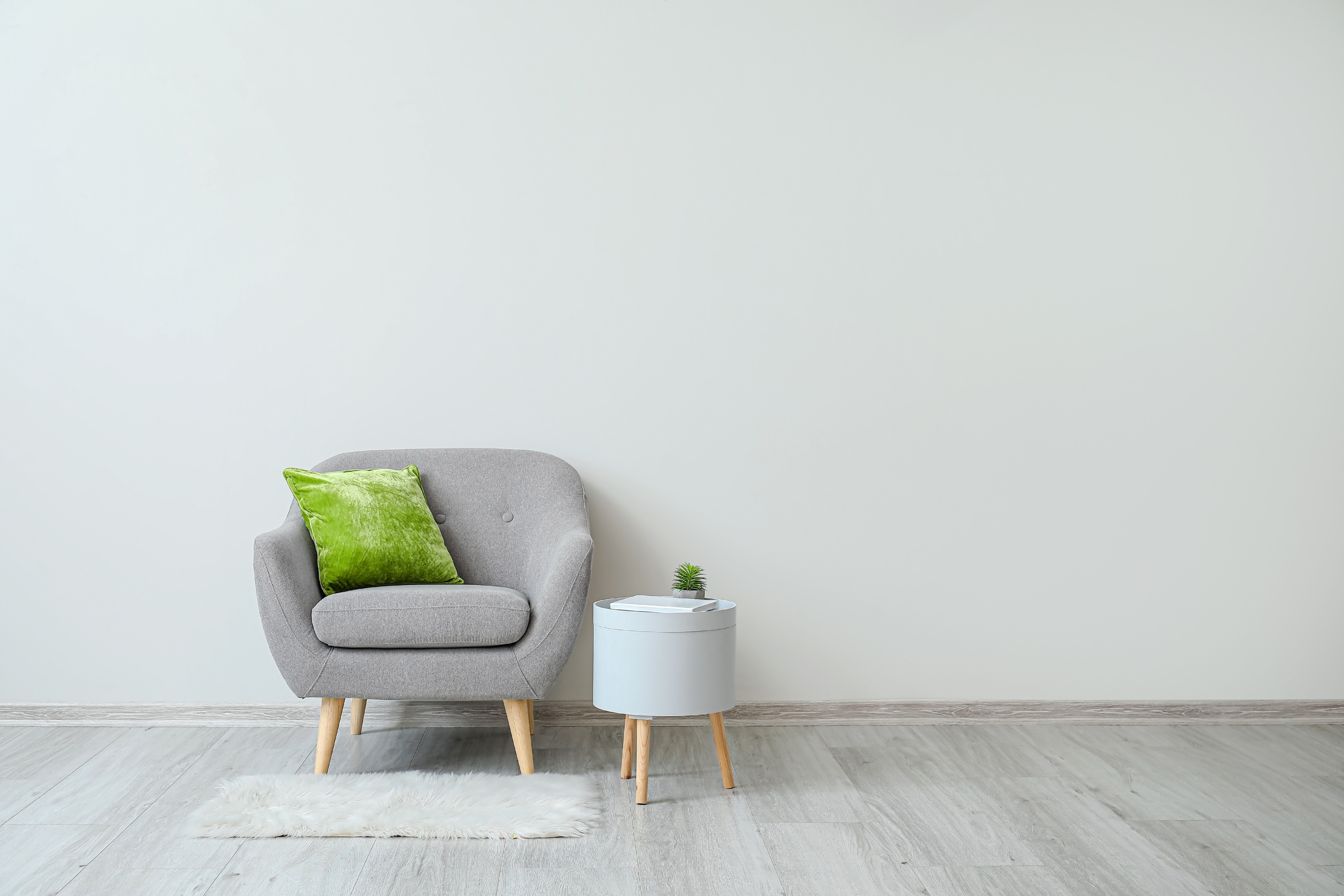 Stylish Armchair with Pillow and Table near Light Wall in Room